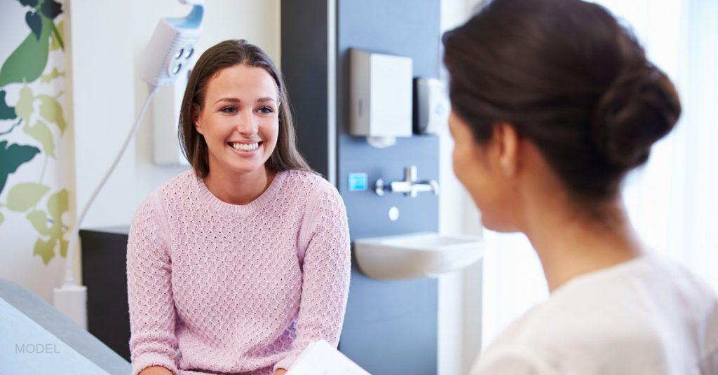 Woman smiling at doctor during consultation. (Model)